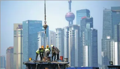  ?? REUTERS ?? Workers work at a constructi­on site in front of Shanghai’s financial district of Pudong.