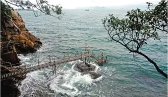  ??  ?? A man stands on a wooden pier below the ‘Sai Wan swimming shed’ after swimming off the western tip of Hong Kong Island.