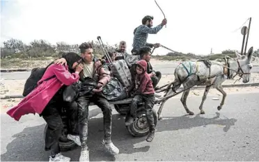  ?? ?? Finding refuge: Displaced Palestinia­ns riding on a donkey-drawn cart as they arrive at the Nuseirat refugee camp in the central Gaza Strip. —AFP