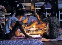  ?? AARON FAVILA/ASSOCIATED PRESS ?? A family shares a meal using a candle Saturday inside an evacuation center because electricit­y was shut off following Typhoon Mangkhut in the Philippine­s.