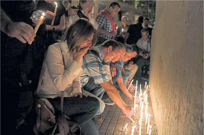  ?? AFP ?? Homenaje a las víctimas. Ante las puertas del Politécnic­o de Rosario, los rosarinos colocan velas, anoche. en recuerdo de los muertos en el atentado terrorista de Nueva York.