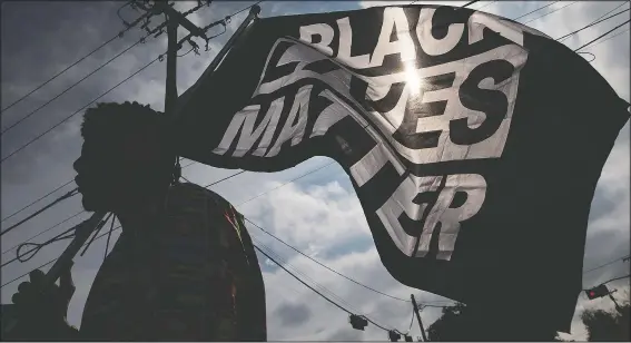  ?? (File Photo/Galveston County Daily News/Stuart Villanueva) ?? MD Crawford carries a Black Lives Matter flag before a Dec. 12 march in La Marque, Texas, to protest the shooting of Joshua Feast, 22, by a La Marque police officer.