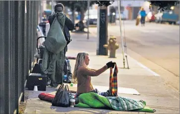  ?? Al Seib Los Angeles Times ?? A WOMAN awakened by LAPD officers on a sidewalk in Venice picks up her belongings. Los Angeles police have shot and killed two homeless people in the neighborho­od in the last twomonths.