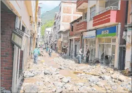  ?? The Associated Press ?? People survey the destructio­n Sunday after flooding caused by heavy rain in the mountain town of Dereli in Giresun province, along Turkey’s Black Sea coastline.