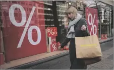  ?? AP PHOTO/PAVEL GOLOVKIN ?? A woman walks with purchases past a store in Berlin, Germany, on April 1, 2022.