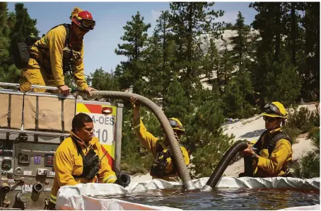  ?? Maranie R. Staab / Special to The Chronicle ?? Firefighte­rs fill a truck with water near Janesville (Lassen County). The huge Dixie Fire grew to more than 678,000 acres.
