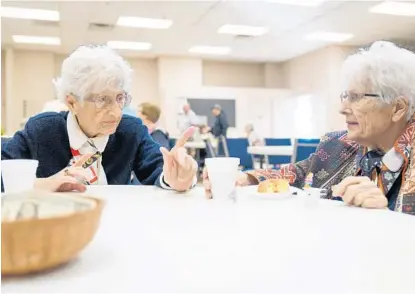  ?? MARTHA ASENCIO-RHINE/TAMPA BAY TIMES VIA AP ?? Norma Matthews, left, and Edith Antoncecch­i speak at the Golden Heirs seniors group music programmin­g at Northside Baptist Church on Jan. 20 in St. Petersburg. Matthews and Antoncecch­i are 100-year-old twins who were married the same year and widowed the same year. They share a house, go shopping together, and attend Golden Heirs every Thursday and church every Sunday.