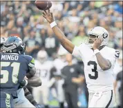  ??  ?? Raiders quarterbac­k EJ Manuel, right passes over Seattle’s Barkevious Mingo (51) during the first half of Thursday’s game.