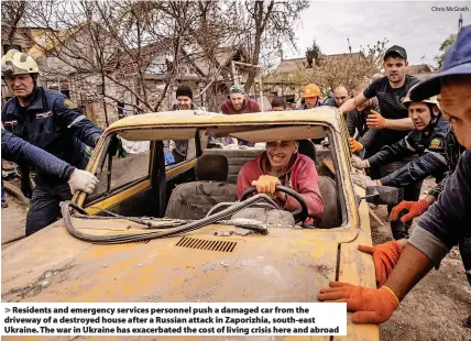  ?? Chris McGrath ?? Residents and emergency services personnel push a damaged car from the driveway of a destroyed house after a Russian attack in Zaporizhia, south-east Ukraine. The war in Ukraine has exacerbate­d the cost of living crisis here and abroad