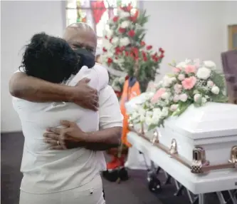  ?? AP FILES ?? Darryl Hutchinson ( facing camera) is hugged by a relative during a funeral service in July at the Metropolit­an Baptist Church in Los Angeles for Lydia Nunez, who was Hutchinson’s cousin. Nunez died from COVID- 19.