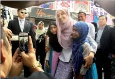  ??  ?? Nurul poses for a photo opportunit­y with two girls on arrival at the venue.