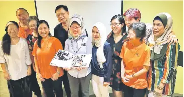  ??  ?? Fatimah shows a book on palliative care while posing with staff from Two Tree Lodge Hospice Kuching, SGH Palliative Care Centre, National Cancer Associatio­n and Kuching Life Care.