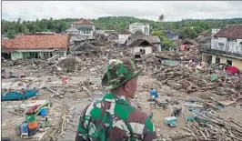  ?? DIMAS ARDIAN/BLOOMBERG NEWS ?? An Indonesian soldier assigned to the rescue and recovery effort surveys the damage Tuesday in Sumur village. Officials raised the nation’s death toll from the tsunami to 429.