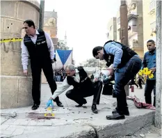  ?? SAMER ABDALLAH/ GETTY IMAGES ?? Egyptian security members and forensic police inspect the site of a gun attack outside a church south of Cairo on Friday. A gunman opened fire at the church, killing at least nine people before police shot him dead.