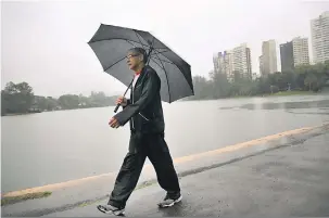  ?? Gina Mardones ?? O clima não intimidou o comerciant­e Romeu Pereira, que saiu para a caminhada diária de guarda-chuva