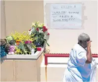  ??  ?? A woman wipes tears away after leaving flowers