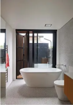  ??  ?? ABOVE The main bathroom also opens right up, this time through sliders that connect to an outdoor shower. Bifold shutters add another layer of detailing to this room, while offering privacy, and beautiful light and shadows during post-surf soaks.