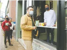  ?? JULIE OLIVER ?? About a dozen people braved a downpour to line up outside Cantina Gia Friday as the new Bank Street restaurant owned by Chris Schlesak, right, promised free food to the first 10 people at its opening.