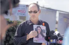  ?? JOSE A. IGLESIAS/EL NUEVO HERALD ?? Fred Guttenberg holds a picture of his slain daughter, Jaime, as he listens to questions from the media during a press conference Monday in front of Marjory Stoneman Douglas High School in Parkland, Fla.