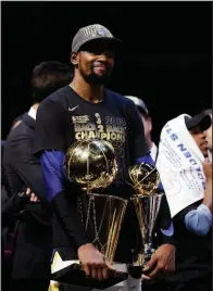  ?? AP/TONY DEJAK ?? Kevin Durant of the Golden State Warriors holds the NBA championsh­ip and MVP trophies after the Warriors defeated the Cleveland Cavaliers 108-85 in Game 4 of the NBA Finals on Friday night in Cleveland. Durant was named Finals MVP for the second...