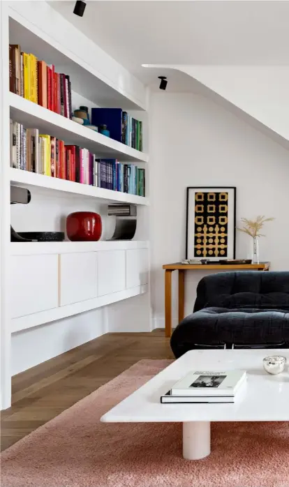  ??  ?? Living room The two ‘Soriana’ sofas were designed by Tobia and Afra Scarpa for Cassina in the 1970s. In the middle sits a marble coffee table designed by Angelo Mangiarott­i, also in the 1970s,
on top of a pink rug from Tai Ping. Built-in shelving that stretches from here into the dining room houses a vast collection of books, ceramics and objets d’art. Displayed on the console is
Early Work, a piece by Victor Vasarely