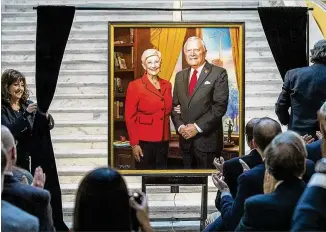  ?? PHOTOS BY ALYSSA POINTER / ALYSSA.POINTER@AJC.COM ?? The official portrait of Gov. Nathan Deal and wife Sandra is unveiled during a news conference Thursday at the Georgia Capitol. The scales of justice reflect Deal’s criminal justice overhaul, and the crane signifies the constructi­on of a judicial complex that will soon bear his name.