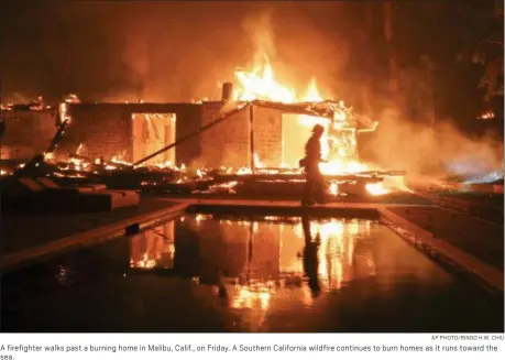  ?? AP PHOTO/RINGO H.W. CHIU ?? A firefighte­r walks past a burning home in Malibu, Calif., on Friday. A Southern California wildfire continues to burn homes as it runs toward the sea.