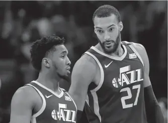  ??  ?? Utah Jazz center Rudy Gobert, right, talks with guard Donovan Mitchell during Saturday’s game against the Detroit Pistons. Both players have tested positive for the coronaviru­s. Gobert's test results forced the NBA to suspend the season.