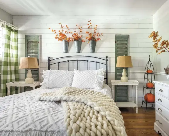  ??  ?? |TOP| FALL DREAMSCAPE. A big chunky throw, real pumpkins and faux branches add just the right amount of fall to the bedroom. “The vintage shutters behind the nightstand­s are green on one side and white on the other,” Jenny says. “The green goes from fall through Christmas. In the spring and summer, I flip it to the white side.” Buffalo-check curtains are the perfect warm pattern for fall and winter.