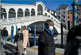  ?? PHOTOS BY CLAUDIO FURLAN — LAPRESSE ?? A man wearing a protective mask walks past the Ponte di Rialto (Rialto Bridge) in Venice, Italy, Friday.