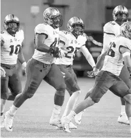  ?? JOHN MINCHILLO/ASSOCIATED PRESS ?? UCF defensive lineman Seyvon Lowry, second from left, celebrates with teammates after intercepti­ng a pass against Cincinnati last week, his second pick of the season.