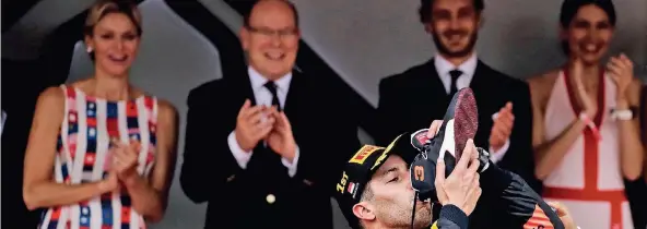  ?? FOTO: REUTERS ?? Daniel Ricciardo trinkt den Sieger-Champagner aus seinem Schuh. Prinz Albert von Monaco (2.v.r.) und Prinzessin Charlene (l.) schauen begeistert zu.