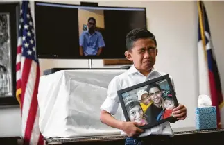  ?? Marie D. De Jesús / Houston Chronicle ?? Walter Escobar, 8, becomes emotional as he holds a photo of his family and father, Jose.