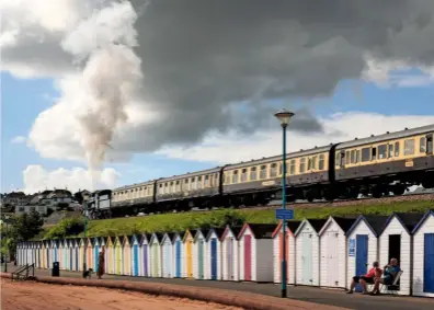  ??  ?? Belching a plume of steam, a train rattles above the uniform beach huts of Goodringto­n Sands.