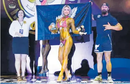  ?? Photos / Paul McSweeney ?? Te Awamutu athlete JustineMil­ler accepts her honours at the WFF World Bodybuildi­ng championsh­ips in Lombok, Indonesia, accompanie­d by Mike Smith (right).