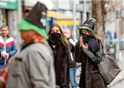  ?? AP PHOTO/PETER MORRISON ?? Tourists cover their faces Tuesday in Dublin’s city centre. The St Patrick’s Day parades across Ireland were canceled because of the outbreak of COVID-19 virus.