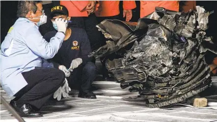  ?? DANY KRISNADHI AFP VIA GETTY IMAGES ?? An official with the National Transporta­tion Safety Committee inspects an engine recovered from the crash site of Sriwijaya Air Flight SJ182 at the port in Jakarta, Indonesia, on Sunday. The Boeing 737-500 crashed into the Java Sea minutes after takeoff on Saturday.