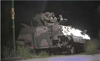  ?? Tsvangiray­i Mukwazhi / Associated Press ?? Zimbabwean soldiers keep watch from an armored vehicle after three explosions were heard early Wednesday in the capital of Harare.