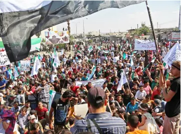  ??  ?? Syrians wave flags during a demonstrat­ion in the rebel-held city of Idlib, in support of the agreement between Turkey and Russia, to avert an assault on Syria’s last major rebel stronghold. — AFP photo