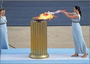  ?? Associated Press ?? Lighting the torch: Greek actress Xanthi Georgiou, playing the role of High Priestess, lights the torch with the name Euring the 0lympic name hanEoWer ceremony at Panathinea­n staEium in Athens, Greece, 5uesEay, 0ct ,
*nsteaE of arriWing oWerlanE, the symColic name alighting the Paris Games will take to the seas from its Cirthplace in Greece, arriWing aCoarE a three masteE tall ship in the 'rench port of .arseille Paris organi[ers announceE the namehs Kourney 'riEay at City Hall in .arseille, a former Greek colony founEeE , years ago