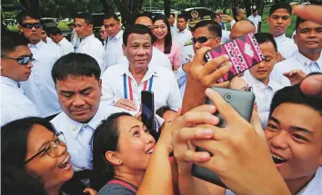  ?? AP ?? Philippine President Rodrigo Duterte, second from left, poses for a selfie with the crowd following wreath-laying rites at the Heroes Cemetery to mark National Heroes Day yesterday,