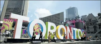  ?? REBECCA BLACKWELL/AP FILES ?? Workers install artwork near Toronto City Hall ahead of this summer’s Pan Am Games. Tuesday is the deadline for Mayor John Tory to notify the IOC whether the city will bid to host the 2024 Olympics.