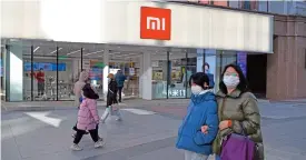  ?? (AFP) ?? People walk past a Xiaomi store in Beijing on Friday