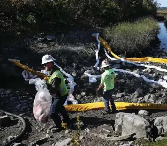  ?? Nancy Lane photoS / heraLd StaFF ?? AFTERMATH: Environmen­tal workers clean up marshland along Route 107 in Revere after a semi hauling diesel fuel rolled over at Brown Circle early Wednesday.