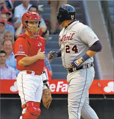  ?? Mark J. Terrill Associated Press ?? MIGUEL CABRERA of the Tigers exchanges words with Angels catcher Dustin Garneau as he scores after hitting a solo home run off Jaime Barria in the first inning. Cabrera also had a two-run single in the eighth.