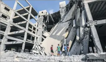  ?? MAHMUD HAMS / AGENCE FRANCE-PRESSE ?? Palestinia­n boys walk through the wreckage of a building that was damaged by Israeli air strikes the day before in Gaza City