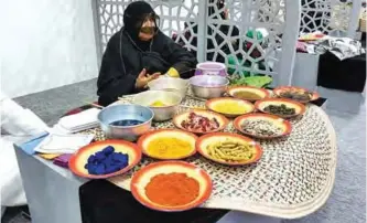  ??  ?? An elderly lady uses natural plant dyes to color clothes and other textile pieces.