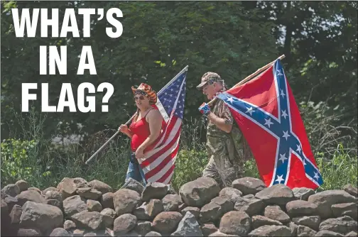  ??  ?? Tourists carry an American flag and a Confederat­e flag as they walk on a pathway at the Gettysburg National Military Park on July 4 in Gettysburg, Pa. (AP/Carolyn Kaster)