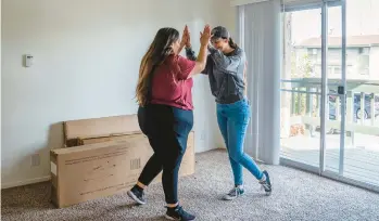  ?? ?? Jacqueline Benitez, left, and her sister high-five Dec. 17 in a new apartment in California.