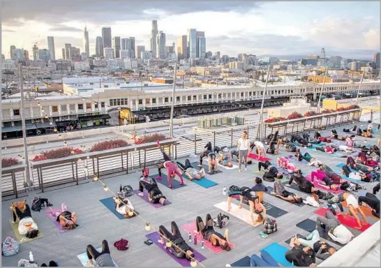  ?? Stephen Camargo benderla.com ?? A SUNSET YOGA event organized by Bender looks toward downtown. Coming soon: Sunset yoga high inside U.S. Bank Tower (super-tall in the center background).